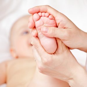 Masseur massaging little baby's foot, shallow focus
